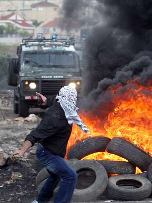 Palestino atira pedra na direção de tropas israelenses durante protesto em Kfar Qaddum Foto: AFP