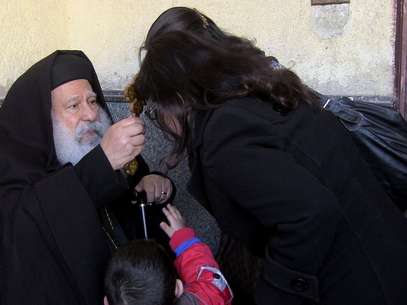  O padre Makary Yunan (esq.) reza por uma família de cristãos na catedral antiga do Cairo Foto: EFE