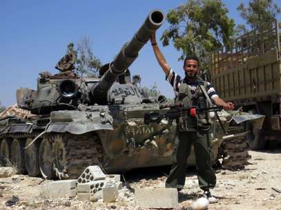 Soldado rebelde posa para a foto junto a um tanque, na cidade de Sermin Foto: AFP
