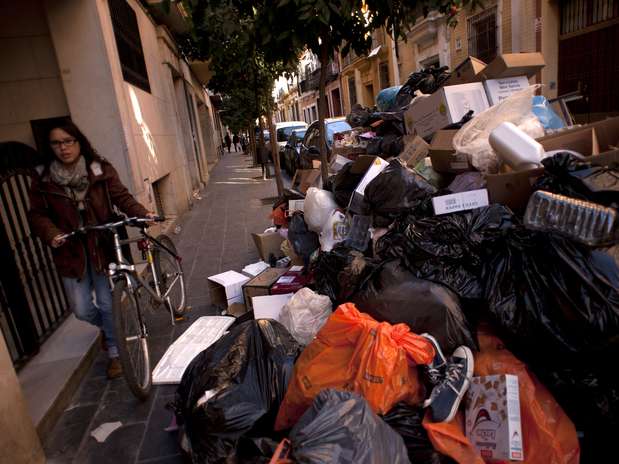 Ciclista passa ao lado de montanha de lixo acumulado em rua de Sevilha, no sul espanhol Foto:  / AFP