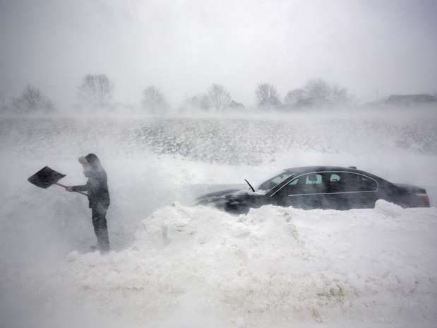 Mulher usa pá para abrir caminho para o seu carro em meio à nevasca, em Portland, Maine Foto: AP