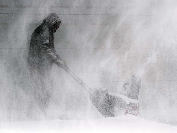 Tom McReynolds tenta remover a neve da entrada da casa de um vizinho em Wichita, Kansas Foto: AP