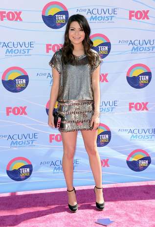 Miranda Cosgrove posa com minivestido metalizado com tachas nas mangas, gola e saia, criando efeito de babado. O modelo é sofisticado e jovial ao mesmo tempo, mas os sapatos parecem não acompanhar o luxo da roupa. Escarpins clássicos, preto, nude ou coloridos teriam ficado melhor Foto: Getty Images