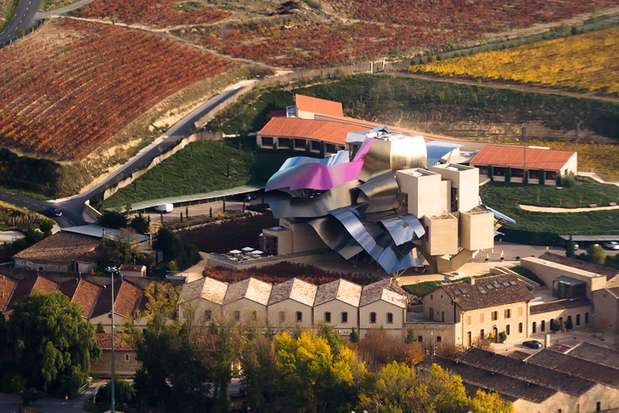 Hotel Marques de Riscal (Espanha): o telhado surpreendente é feito em aço prateado e dourado e titânio lilás, cores inspiradas nas tampas de prata, malha de fio de ouro e conteúdos roxos de uma garrafa de Marqués de Riscal. Mas as formas liquescente do telhado também evocam os prazeres do vinho em geral. O edifício é, em outras palavras, um instantâneo semi-abstrato de alguns vinhos da Gran Reserva girando em torno da bacia ampla de um recipiente grande Foto: Divulgação