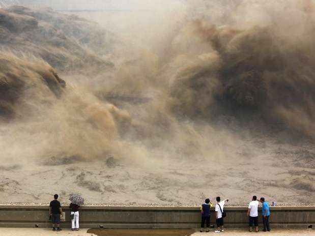 Visitantes observam uma represa ser aberta no rio Amarelo, em Jiyuan, na China Foto: AFP